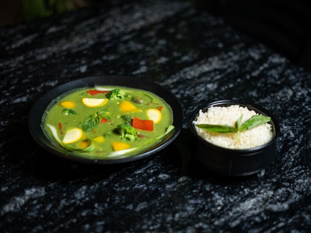 Un plato de sopa verde con un plato de arroz blanco al lado.