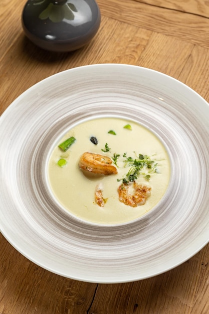 Un plato de sopa con vieiras y cebollas verdes