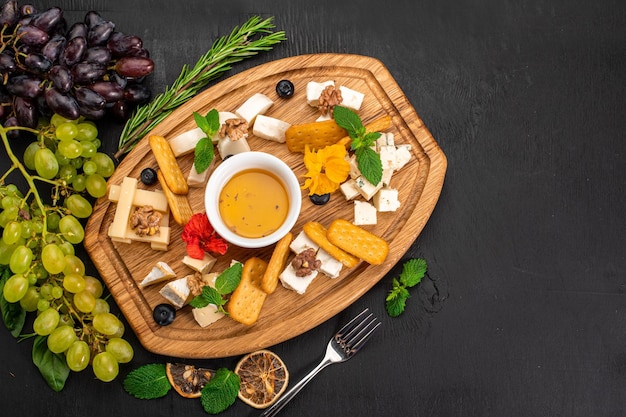 Plato de surtido de tupes de queso con miel sobre fondo de madera