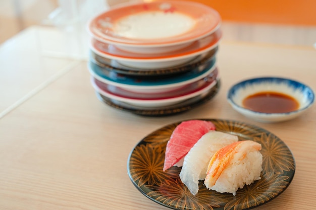 Un plato de sushi se sienta en una mesa junto a una pila de tazones con salsas.