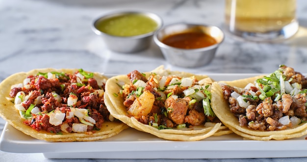 Plato de tacos callejeros mexicanos con carne asada, chorizo y al pastor en tortillas de maíz