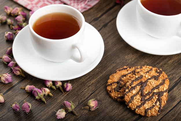 Plato de tarta dulce con chispas de coco, galletas y taza de té en la superficie de madera