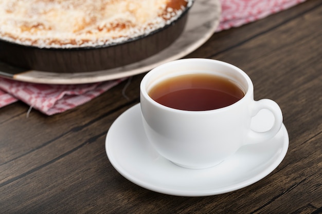 Plato de tarta dulce con chispas de coco y taza de té en la superficie de madera