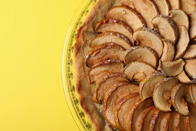 Plato con tarta de manzana sobre fondo amarillo