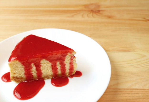 Plato de tarta de queso al horno con salsa de frambuesa servido en mesa de madera