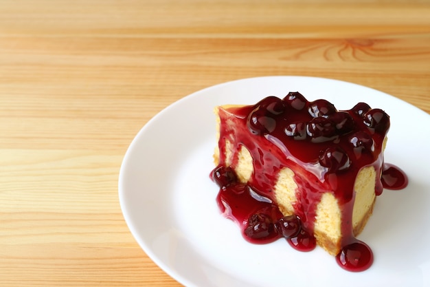 Plato de tarta de queso de arándanos servido en mesa de madera con espacio de copia