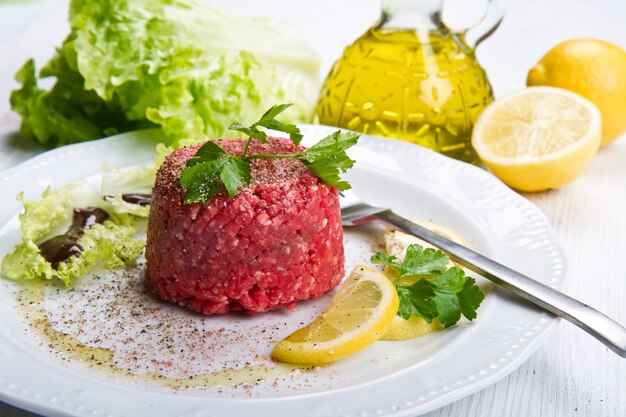 Plato con tartar de carne y rodajas de limón.