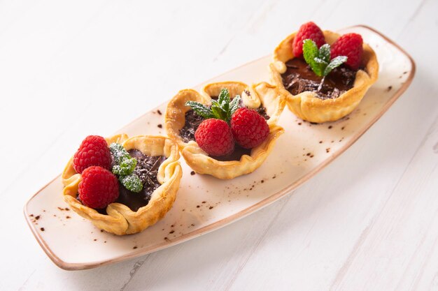 Un plato de tartas de chocolate con frambuesas encima