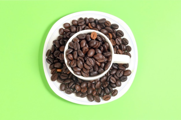 Plato de taza de cerámica blanca de grano de café sobre fondo de color verde