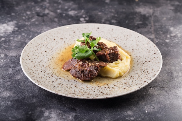 Plato de ternera con puré de patatas y hierbas.