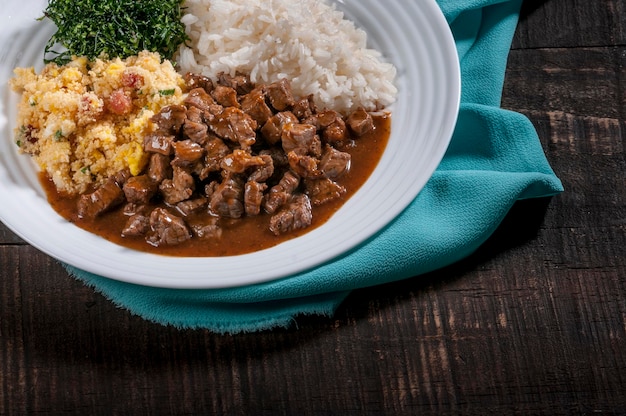 Plato típico brasileño, dados de ternera, arroz, col rizada y huevo rallado.