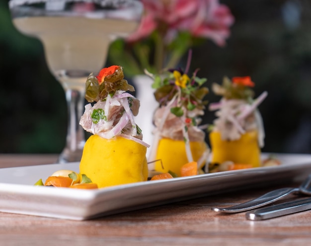 Foto plato típico peruano, causa rellena en una mesa de restaurante.