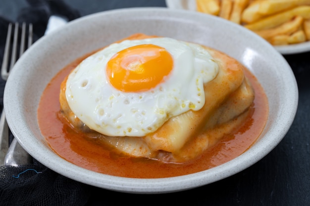 Plato típico portugués francesinha en plato sobre fondo de cerámica negra