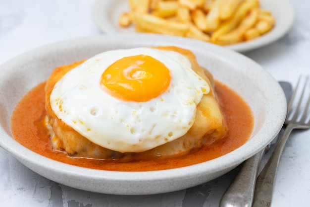 Plato típico portugués francesinha en plato sobre fondo de cerámica