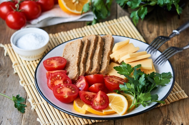 Plato de tomates cherry, queso y pan de centeno en una mesa de madera