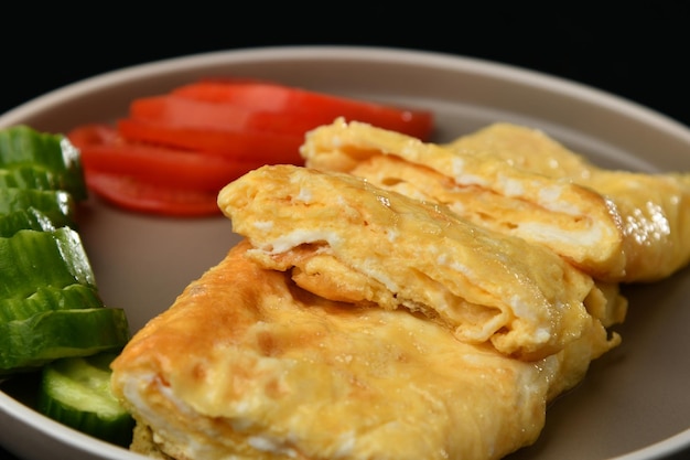 Un plato de tortilla con tomates y pimientos verdes