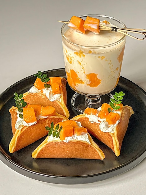 Un plato de tortitas con un vaso de leche y un vaso de crema de mango.