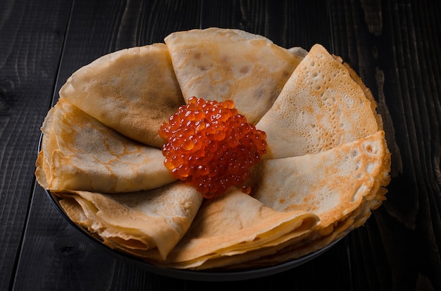 Plato tradicional festivo de panqueques finos con caviar rojo.