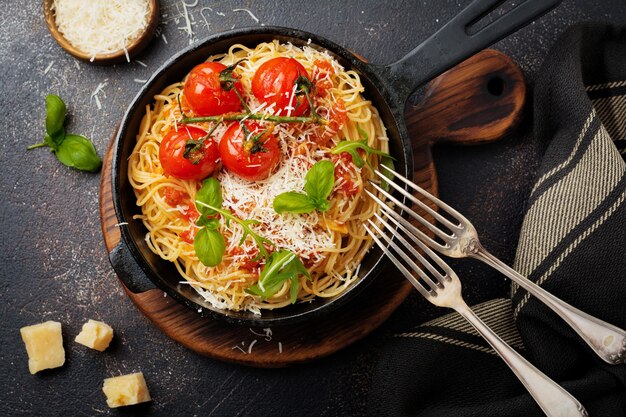 Plato tradicional italiano de espaguetis con salsa de tomate y queso parmesano en una sartén de hierro
