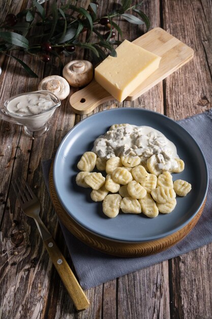 Plato tradicional italiano de ñoquis con salsa cremosa de champiñones y queso