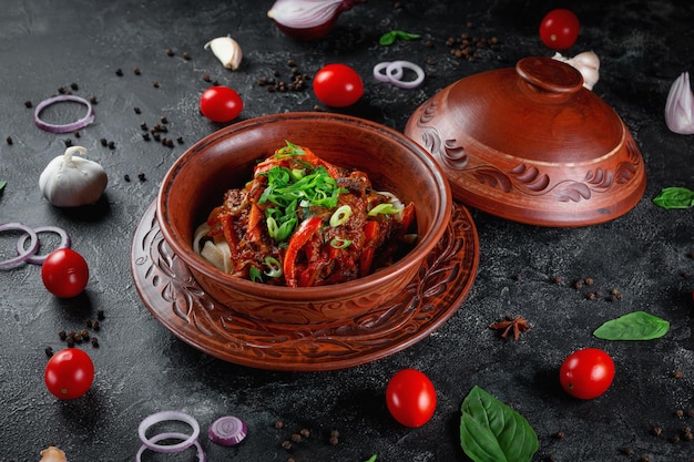 Plato tradicional kazajo Kuirdak Asado aromático de subproductos de carne de cordero con muchas cebollas y verduras en una cazuela de barro