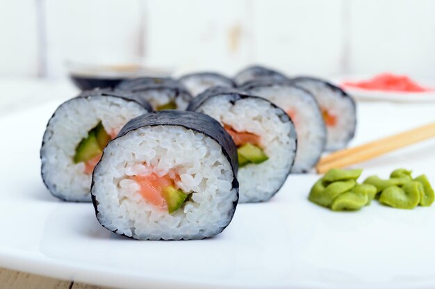 Plato tradicional oriental con rollos de sushi de salmón en un plato blanco Primer plano