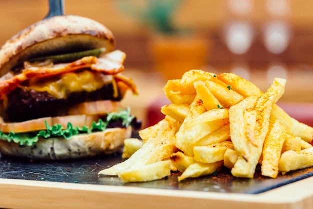 Plato tradicional de patatas fritas y hamburguesa con vidrio sobre mesa rústica