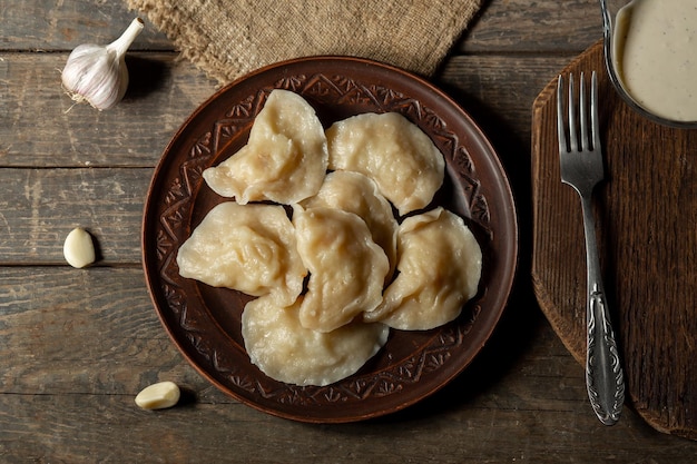 Plato tradicional ucraniano varenyky con patatas servido en un bol con crema agria y raviolis de ajo