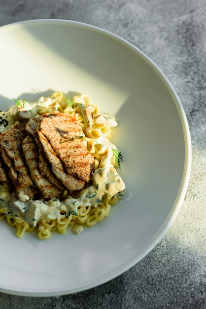 Plato con trozos de carne, pasta, verduras, salsa de foie gras y la tierra de olivo.