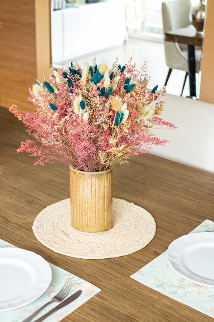 Foto plato y utensilios sobre la mesa decorados con un pequeño arreglo floral