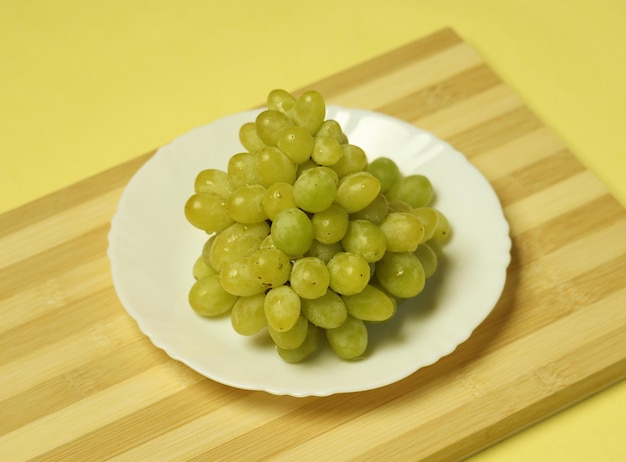 Un plato de uvas verdes sobre una tabla de madera.