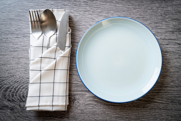 Plato vacío o plato con cuchillo, tenedor y cuchara en la mesa de baldosas de madera