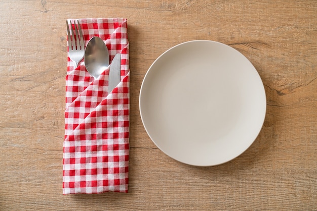 Plato vacío o plato con cuchillo, tenedor y cuchara sobre fondo de baldosas de madera
