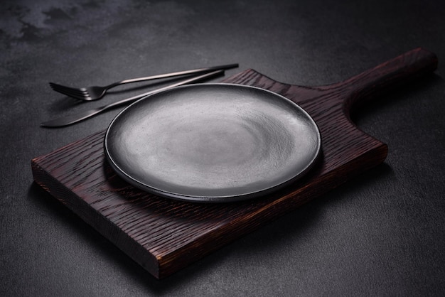 Un plato vacío con un tenedor de cuchillo o una cuchara con una tabla de cortar de madera