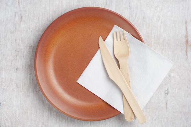 Plato vacío con tenedor de madera y cuchillo de mesa en la mesa vieja, vista superior