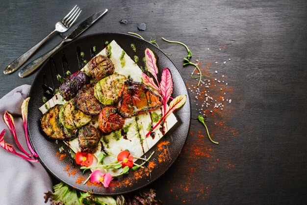 Plato vegano con verduras asadas sobre fondo negro