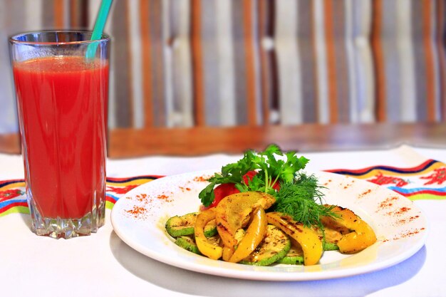 plato para vegetarianos verduras a la parrilla pimentón tomates calabacín hinojo y un vaso de jugo de tomate