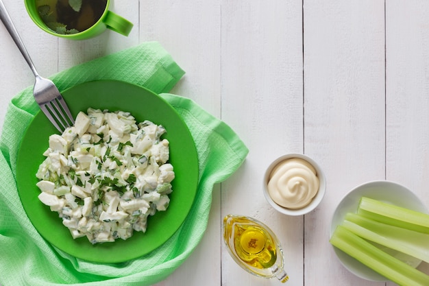 Plato verde de ensalada de apio con aderezo y aceite de oliva