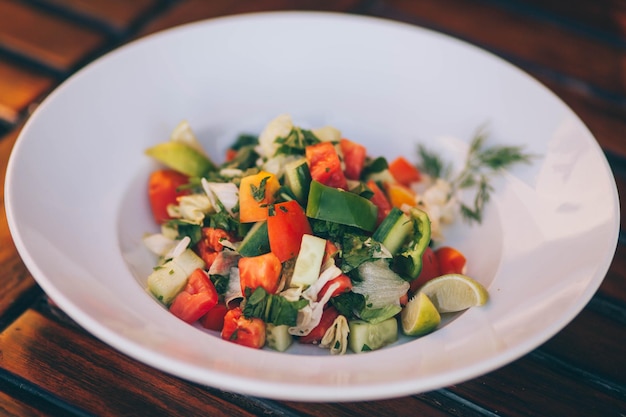 Un plato de verduras con aguacate al lado.