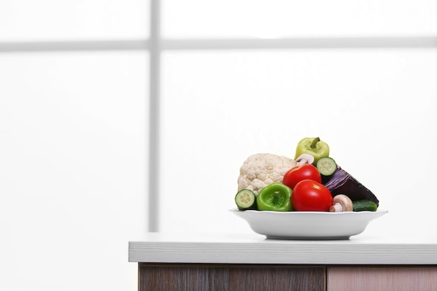 Plato de verduras frescas en una mesa frente al fondo de la ventana