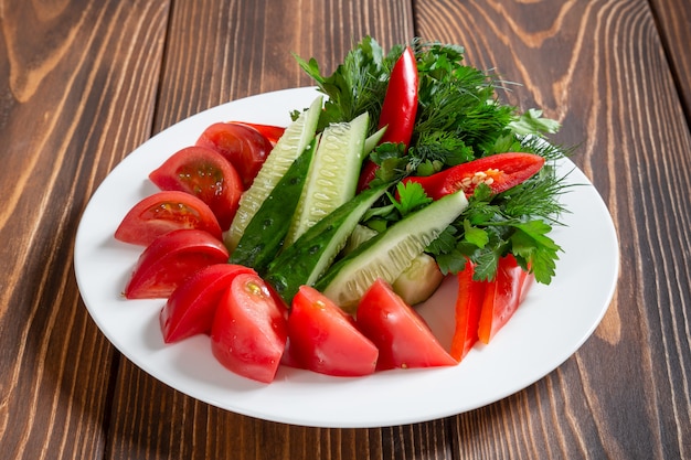 Plato de verduras frescas y verdes en la mesa de madera