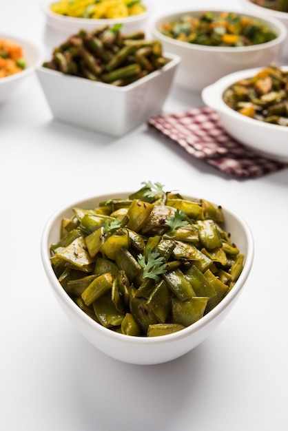 Plato de verduras fritas llamado Flat Green Beans con especias, servido en un cuenco de cerámica, sobre fondo cambiante. enfoque selectivo