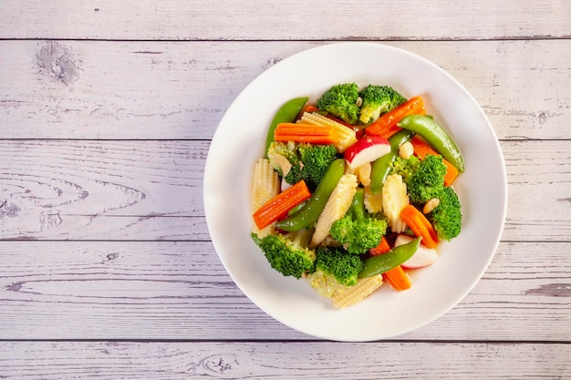 Plato de verduras salteadas en mesa de madera