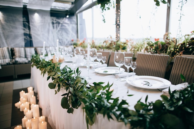 Platos blancos, copas de champán y vino y velas en la mesa de bodas