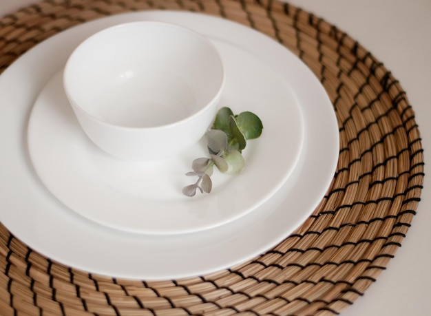 Foto platos blancos y una rama de eucalipto sobre una servilleta de yute