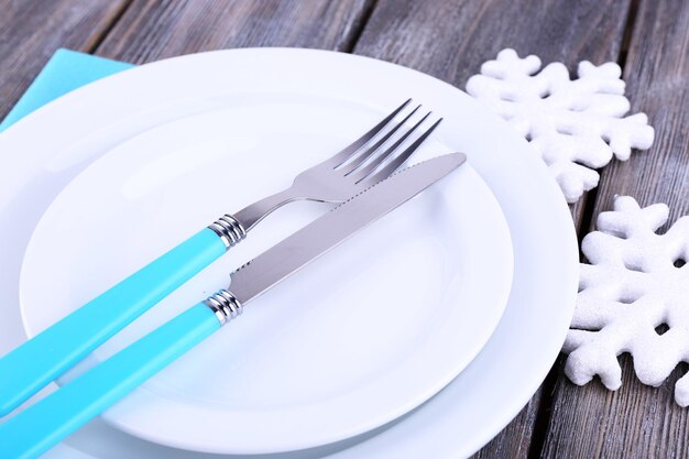 Platos blancos, tenedor, cuchillo y decoración del árbol de Navidad sobre fondo de madera