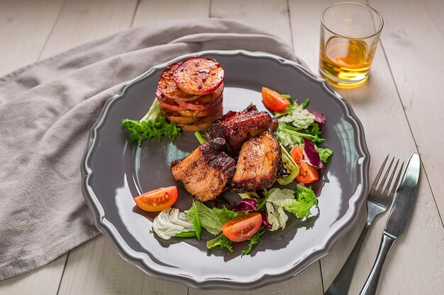 Platos de carne caliente costillas de cerdo a la parrilla con ensalada y manzanas en un plato