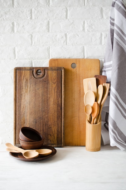 Platos de cerámica, cubiertos de madera o bambú, tablas de cortar y toalla en el interior de la cocina.