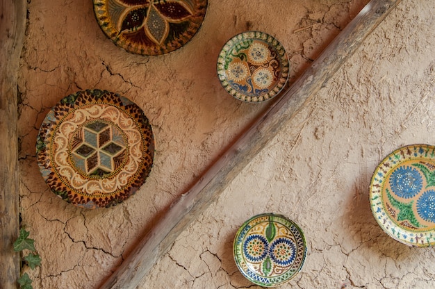Platos de cerámica orientales cuelgan de una pared de arcilla La pared de arcilla está decorada en estilo oriental