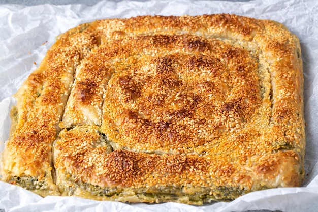 platos de la cocina griega; spanakopita Sésamo en pastel de queso feta de espinacas hecho a mano en el horno. nombre turco; ispanakli borek